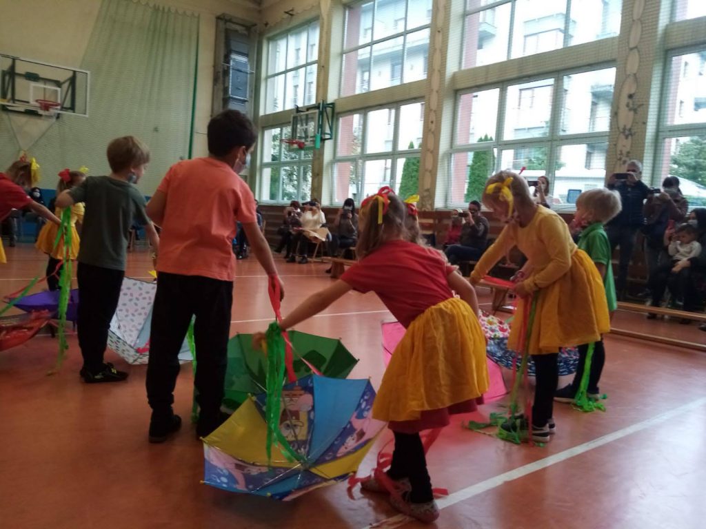 Przedszkolaki tańczące z parasolkami.