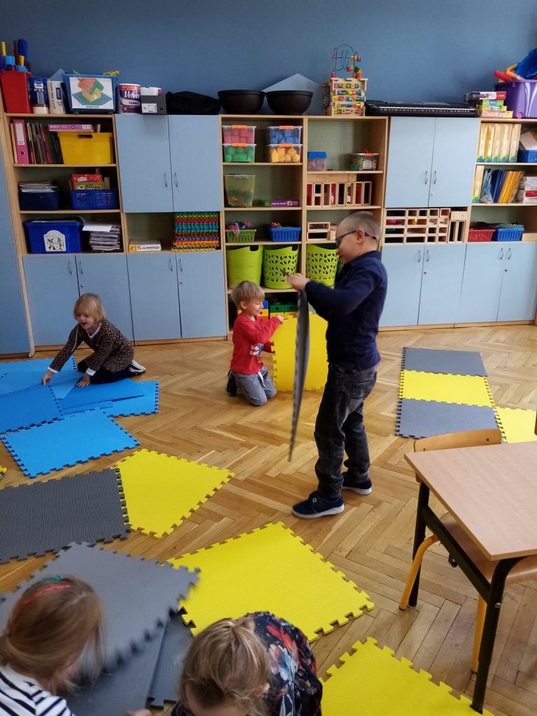 Na zdjęciach przedszkolaki bawiące się na macie.