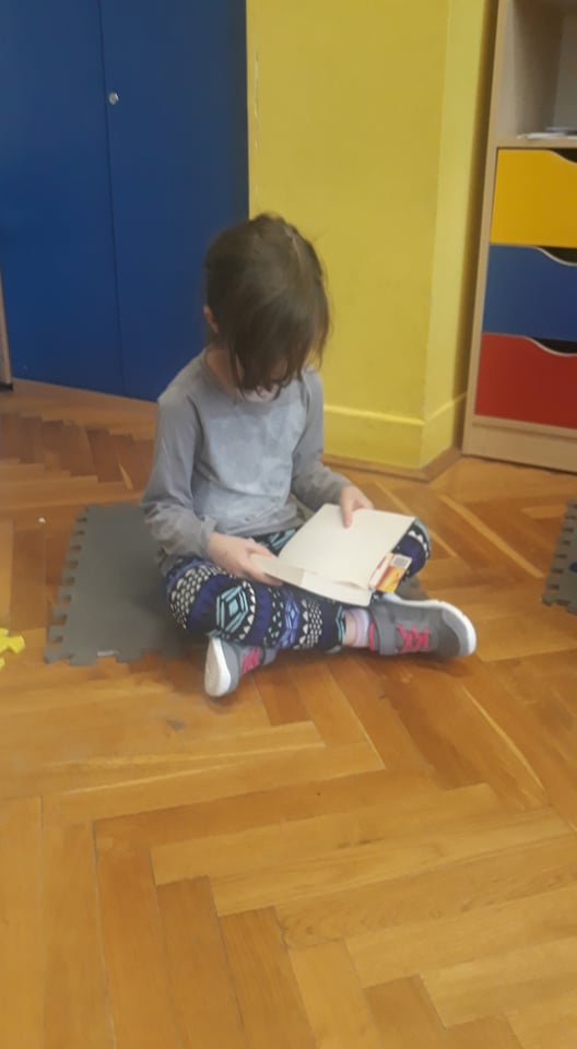 Zdjęcie przedstawia dziecko czytające książkę.