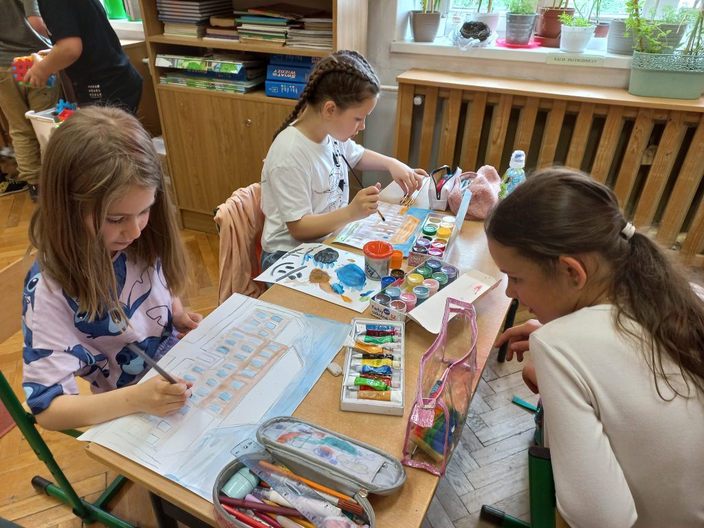 Uczennice klasy 3b malujące budynek szkolny.