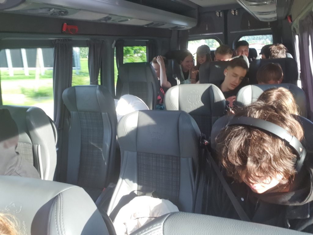 Zdjęcie przedstawia klasę siedzącą w busie.