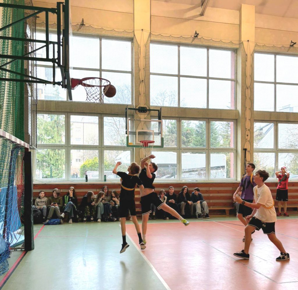 Zdjęcie przedstawia uczniów grających w kosza.